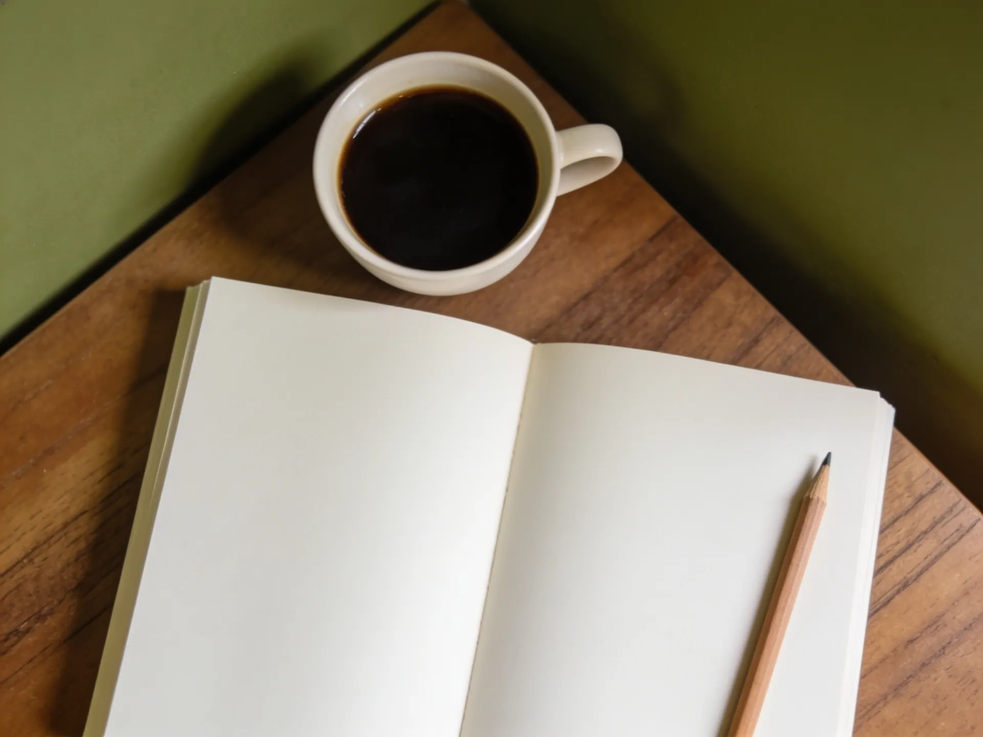 Caderno aberto em branco, lápis e xícara de café vistos de cima sobre uma mesa de madeira